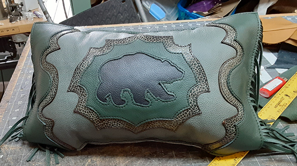 green leather pillow with a bear